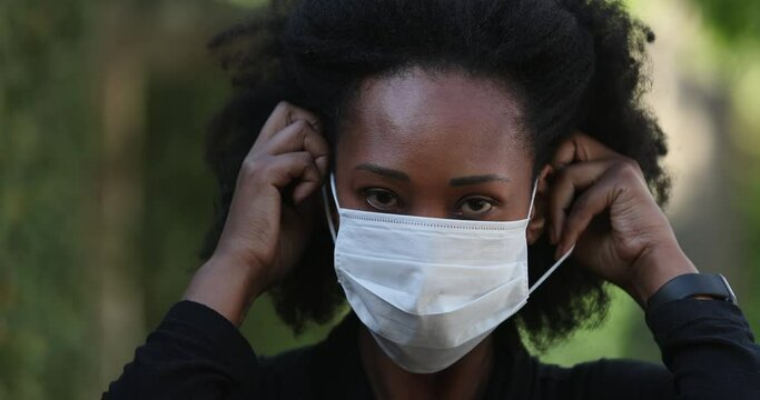 Black Woman Putting Covid-19 Face Mask Outside Looking At Camera