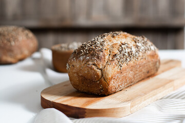 Selective focus. Homemade whole grain bread with seeds in the kitchen with rustic wooden background