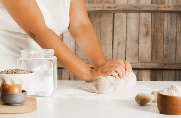 Woman's hands making a dough for a homemade bread, rustic wooden background. Copy space.