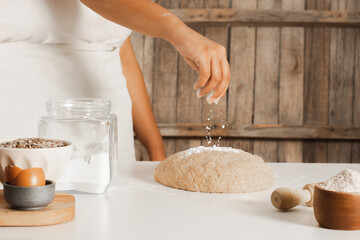 Female chef making shower of flour and ingredients for the dough on the kitchen table. Copy space