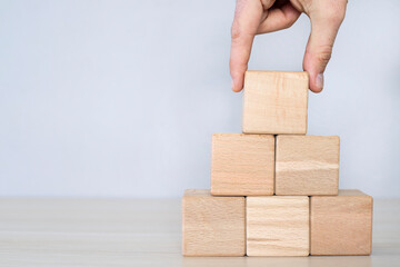 Hand putting and stacking blank wooden cubes on table with copy space for input wording and infographic icon.