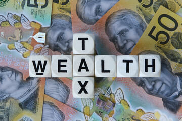 Wealth tax signage on a bed of Australian dollars.