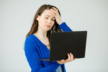 Woman is holding a laptop and has a headache. Fatigue from working on the computer. Woman is sad and tired from working online 