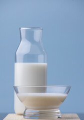 cup of milk with bottle on wood, blue background