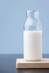 transparent glass milk bottle, on wood, blue background