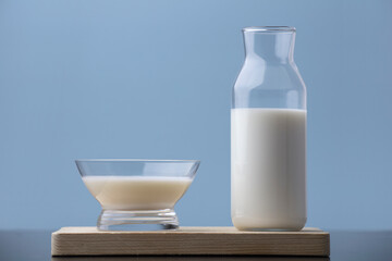 cup of milk with bottle on wood, blue background