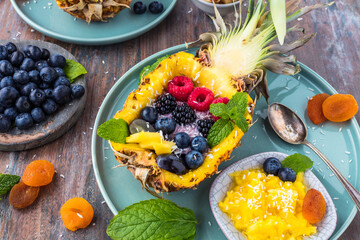 top view of gourmet dessert with halved pineapple and fresh berries on table    