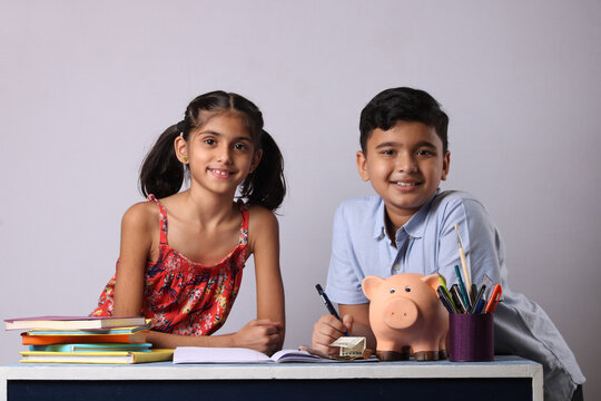 Indian Boy and Girl with piggy bank for future education with books.