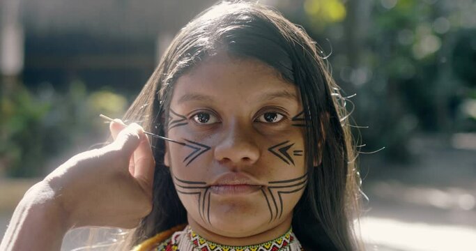 Young Brazilian girl indigenous Pataxó ethnicity doing face painting. 4K.