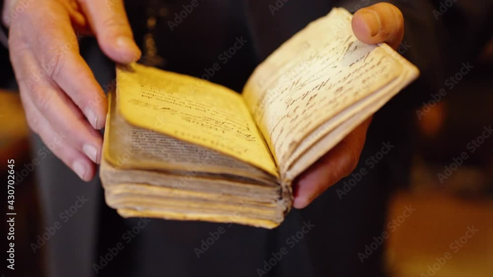 Poster old man with shaky hands standing while holding and turning pages of an old diary inside the library