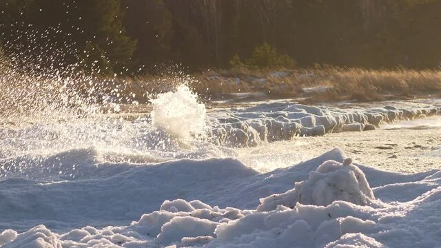 Aggressive and strong ocean waves hitting icy coastline, slow motion