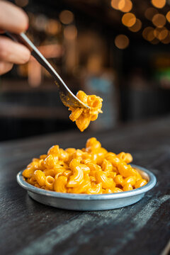 Macarrones con queso. Plato tradicional americano pasta de macarrones y salsa de queso con mano