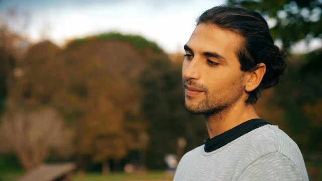 young gay at the park timidly looks at the camera making effeminate gestures