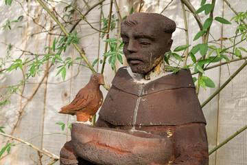 A bird bath statue of St. Francis of Assisi in a backyard garden. - obrazy, fototapety, plakaty