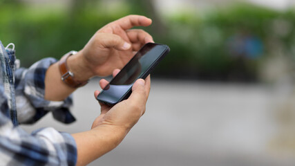 Side view of male hands texting on smartphone while outdoor standing