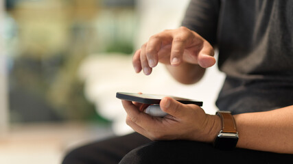A man using smartphone while sitting in blurred background