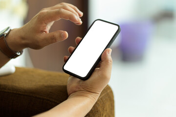 Close up view of male hand using smartphone with mock-up screen in blurred background