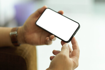 Male holding smartphone with horizontal mock-up screen in blurred background