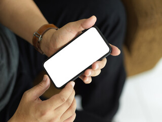 Top view of male hands holding smartphone and showing mock-up screen to camera