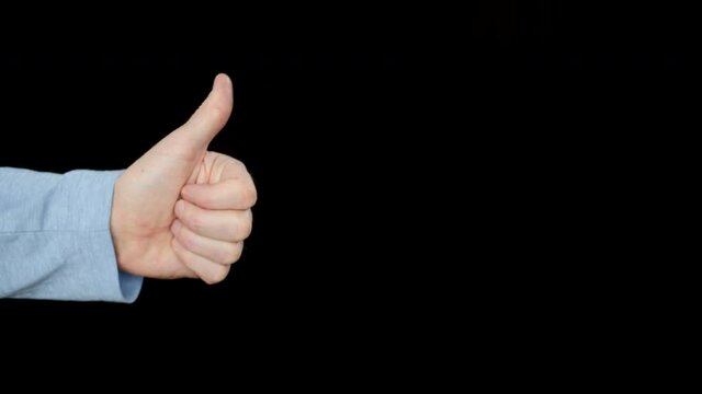 Cropped shot of person showing thumb up gesture. Close-up partial view of human hand showing thumbs up isolated on black background