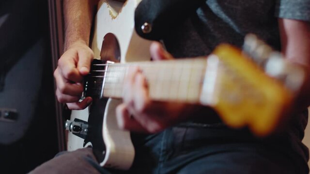 Slow motion close up of an electric telecaster guitars with a guitarists hands playing notes with a pick. Smooth slow motion. Shot in 4K at 120fps