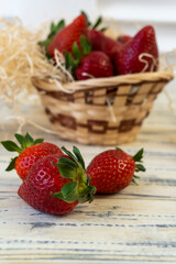 Strawberry in basket and on table on wooden background