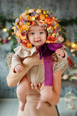 Portrait of a baby in a flower cap. A beautiful baby of 6 months in a hat made of flowers, a small child in a flower wreath.