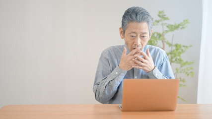 ノートパソコンの前で驚くシニア男性