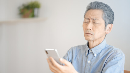 スマートフォンを使う老眼のシニア男性