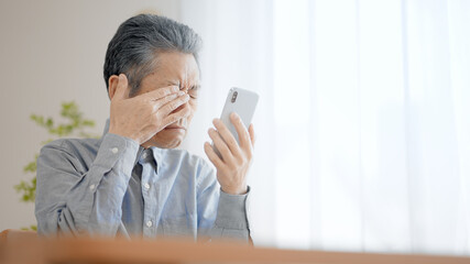 スマートフォンを使う老眼のシニア男性