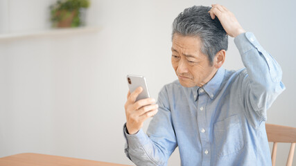 スマートフォンの操作に悪戦苦闘するシニア男性