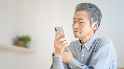 スマートフォンの操作に悪戦苦闘するシニア男性