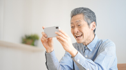 スマートフォンで動画を視聴するシニア男性