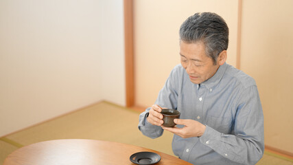 和室でお茶を飲むシニア男性