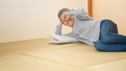 寝っ転がりながらテレビを見るシニア男性