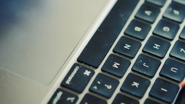 Fingers using touchpad on mac computer with dirt on the keyboard, close up