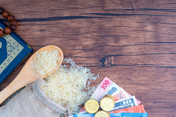 Holy Al Quran, Coins, Banknotes and Rice on wooden background. Zakat concept. Zakat is a form of alm-giving as a religious obligation