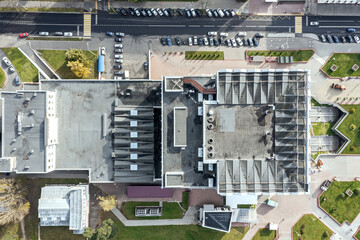 Fototapeta premium shingle roof of city shopping mall with ventilation systems and outdoor lighting. aerial top view