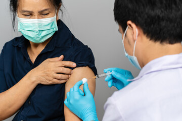 doctor holding syringe and using cotton before make injection to woman in medical mask. Covid-19 or coronavirus vaccine