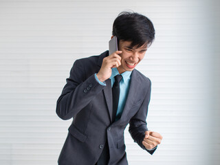 Asian businessman speaking on smartphone and celebrating success