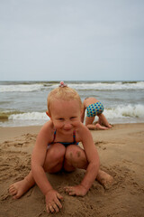 cute 4 year old is playing with sand on a beach