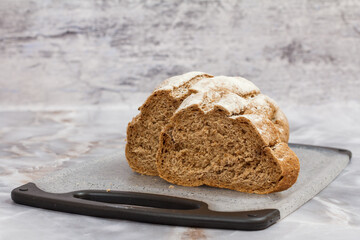 Cut loaf of bread on cutting board on kitchen desk with gray background