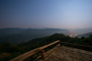 Landscape on a wooden house on a hill The orange forest fire on the mountain at night looked terrifying. It is spreading, causing dust and toxic fumes in northern Thailand.