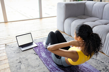 Young Afro American woman doing fitness with trainer online at home. Healthy lifestyle concept