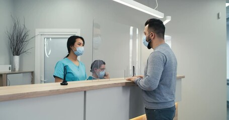 Man in mask speaking with nurse on hospital reception - Powered by Adobe