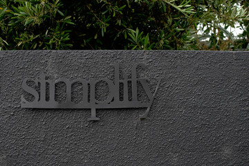 simplify, grey sign on grey wall