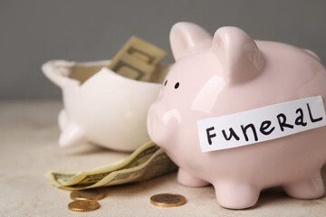 Piggy banks with money and word FUNERAL on light background