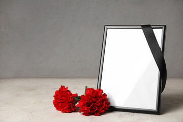 Blank photo frame and carnation flowers on light background
