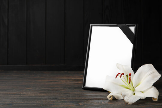 Photo frame and lily flower on dark wooden background