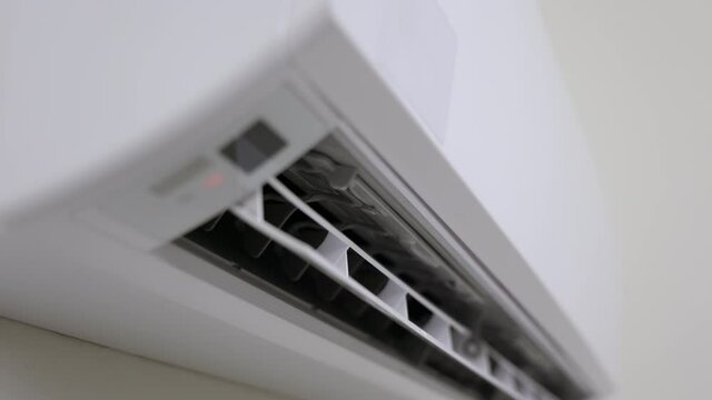 A young man used a remote to turn off the air conditioner. In the living room at home